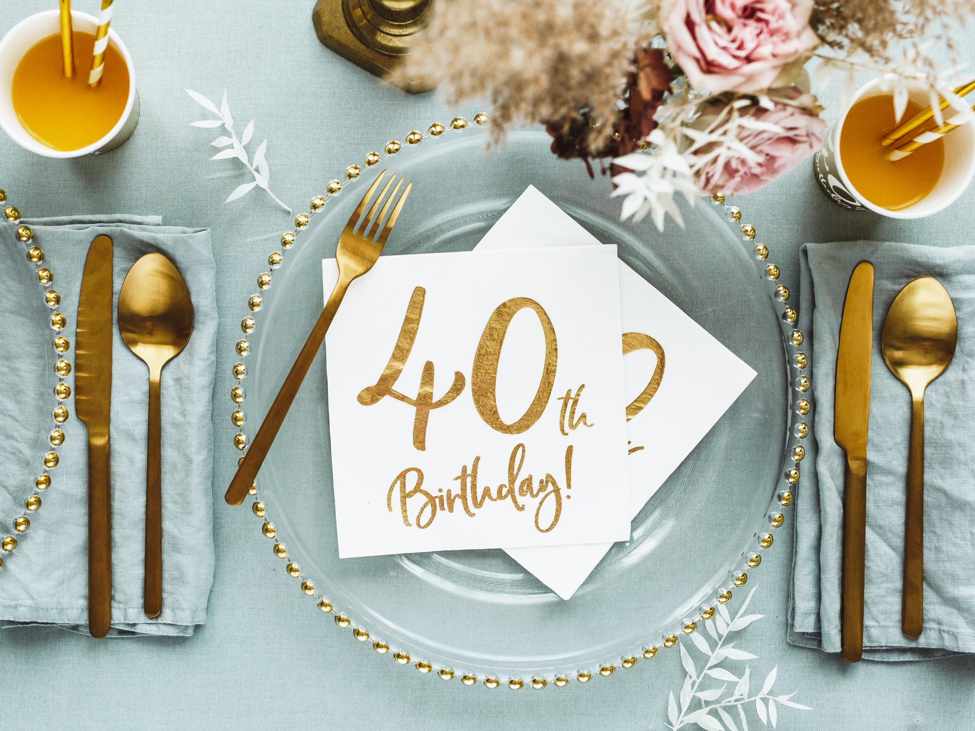 table setting with clear dinner plate, 40th birthday napkin and gold cutlery