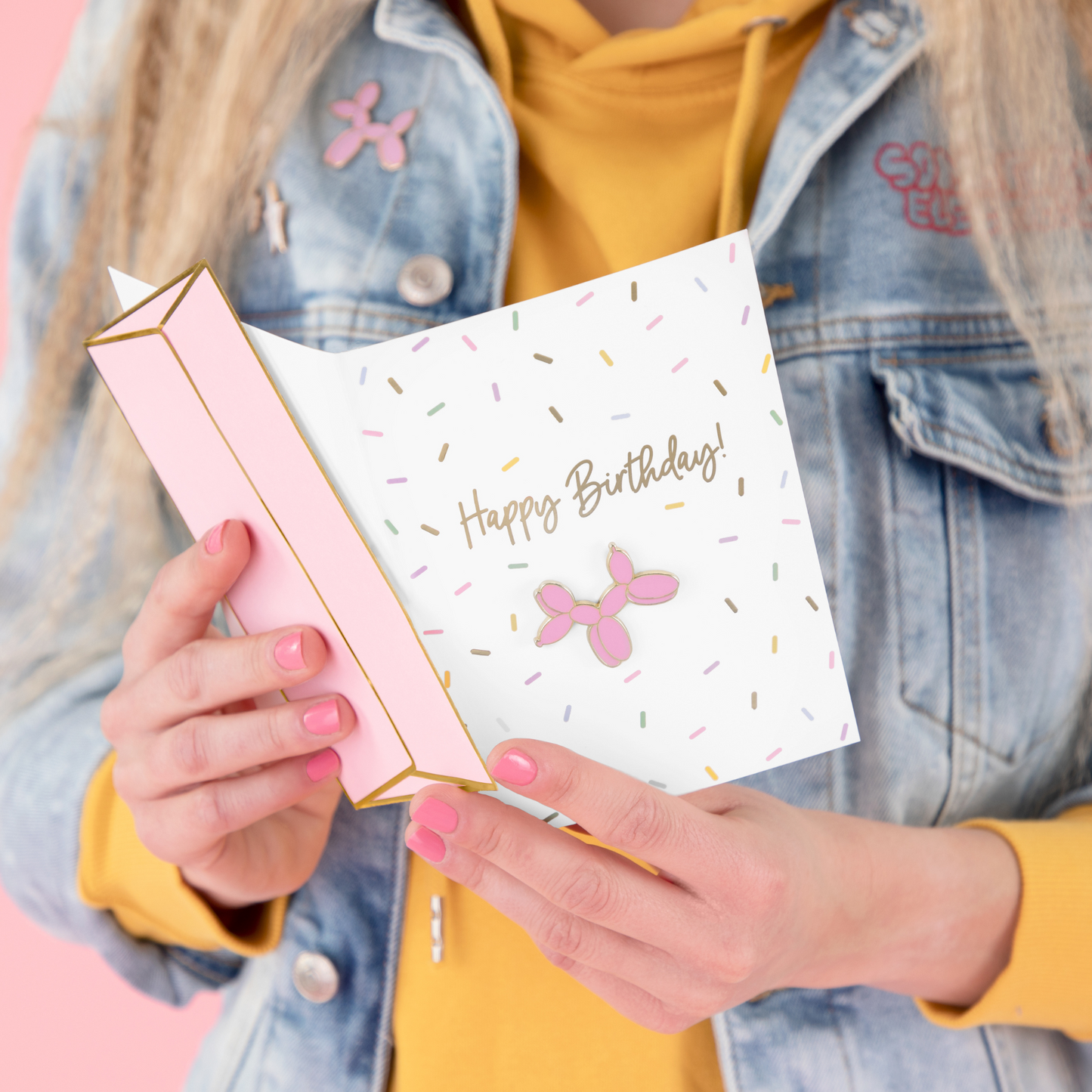 girl holding a birthday card with a balloon dog pin