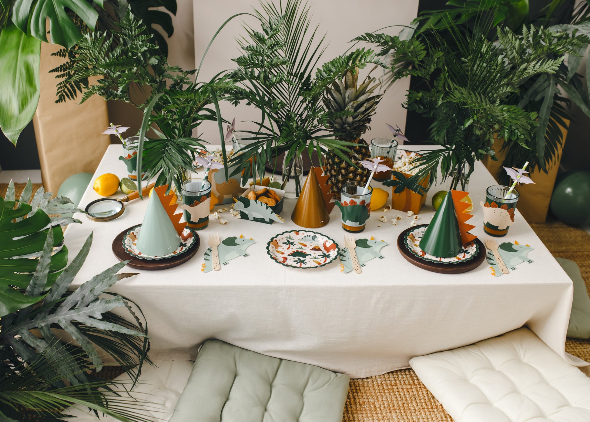 table setup for Dino lover birthday including plates, hats, napkins and treat boxes