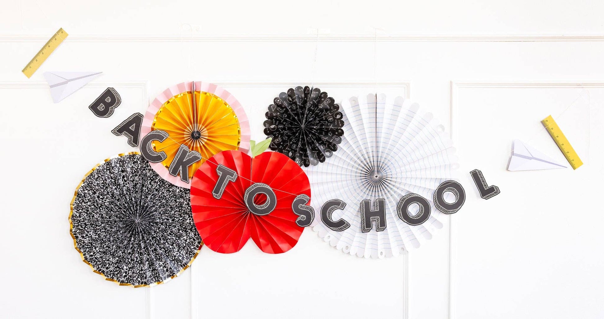 A "Back to School" banner is displayed on a white wall, decorated with colourful paper fans and paper airplanes.