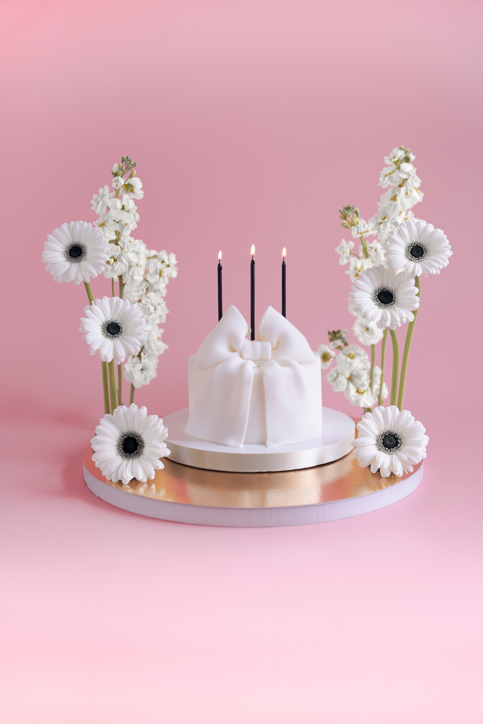 chic black birthday candles on a bow all white cake 