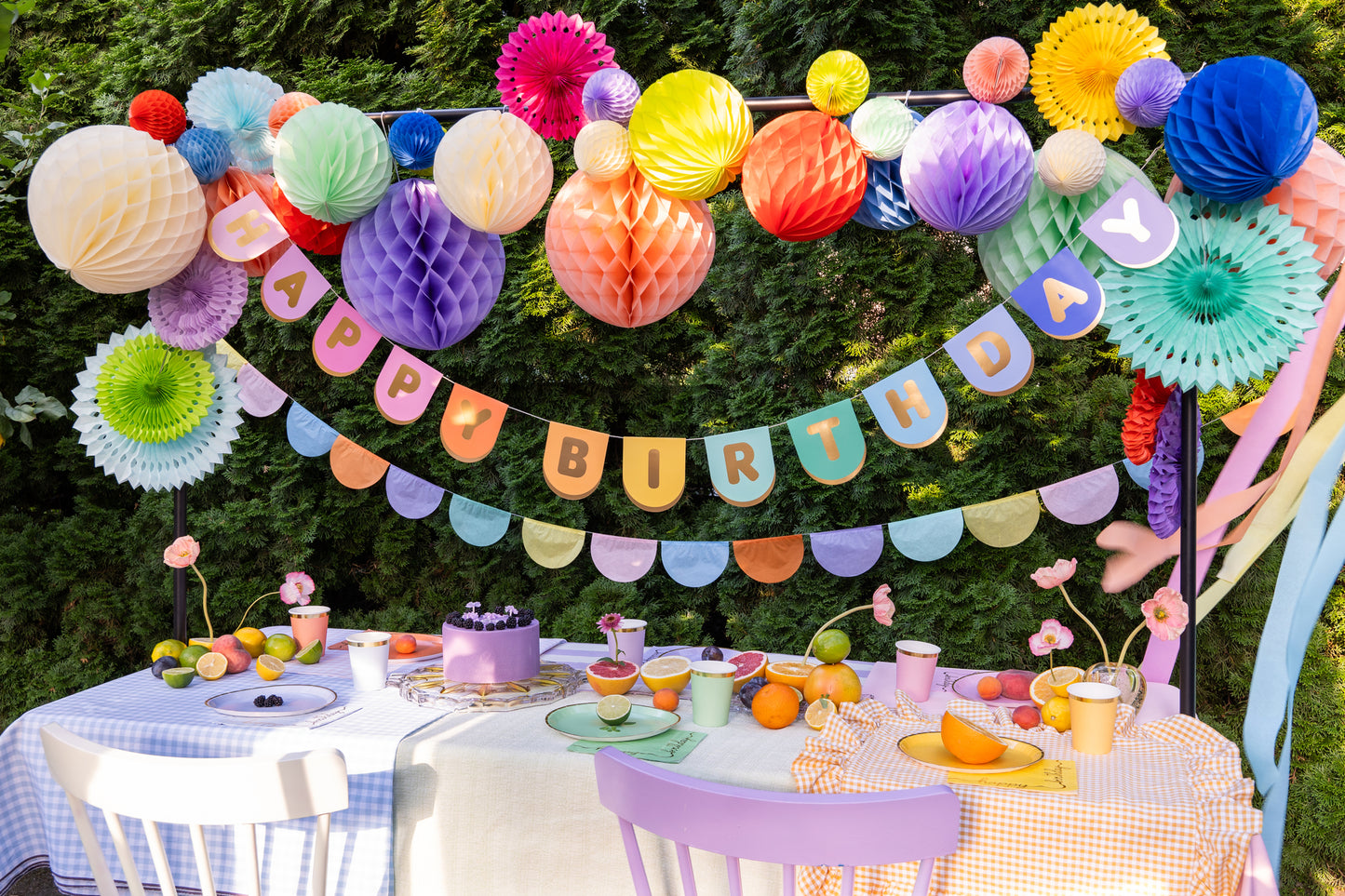 outdoor birthday table setup with colourful birthday banners, paper rosettes, and honey combs