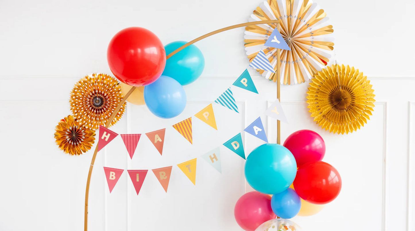 Colorful birthday decorations with balloons and triangular pennant banner spelling "Happy Birthday" in a festive arrangement