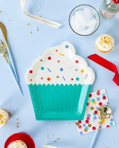 party table with cupcake shaped paper plate, confetti napkins and plastic cutlery