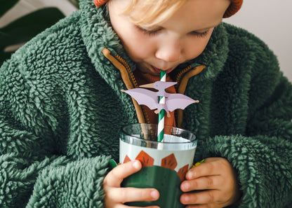 little boy using a Dino straw drinking from a cup with the Dino sleeve