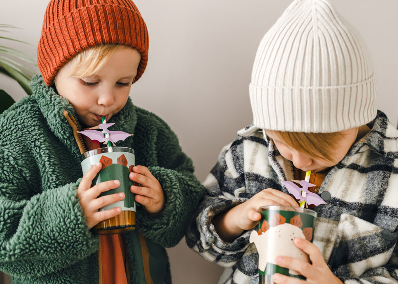 friends drinking from cups with dinosaur sleeves and straws