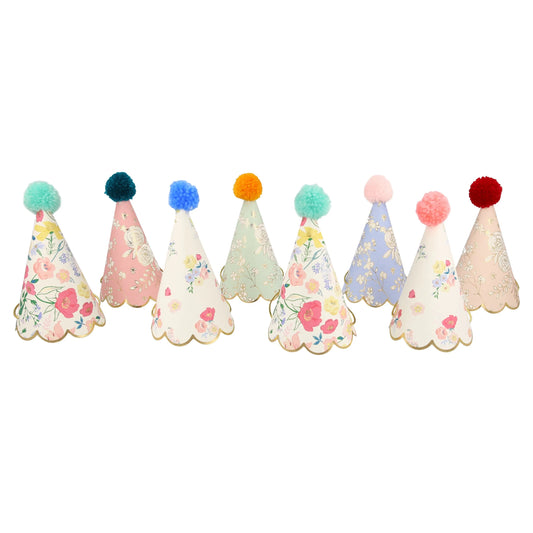 A row of paper party hats with floral designs and pom poms.