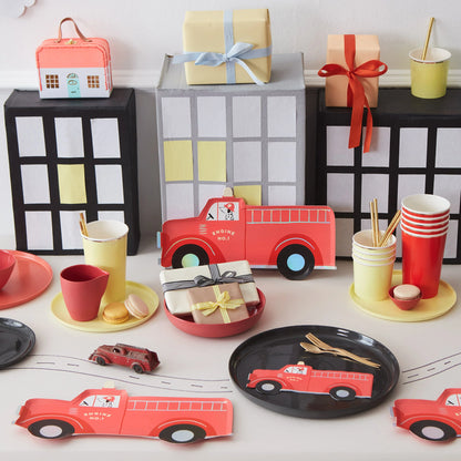 A table topped with firetruck themed party supplies.