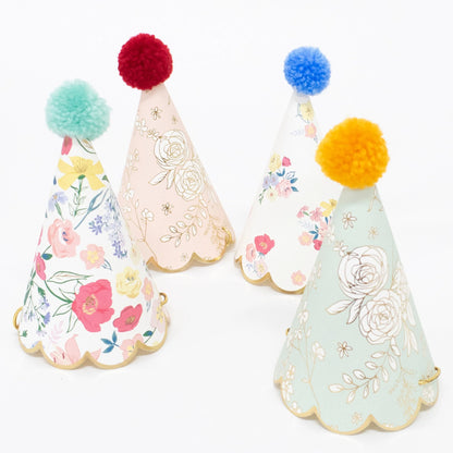 4 floral printed paper party hats with colourful pom poms.