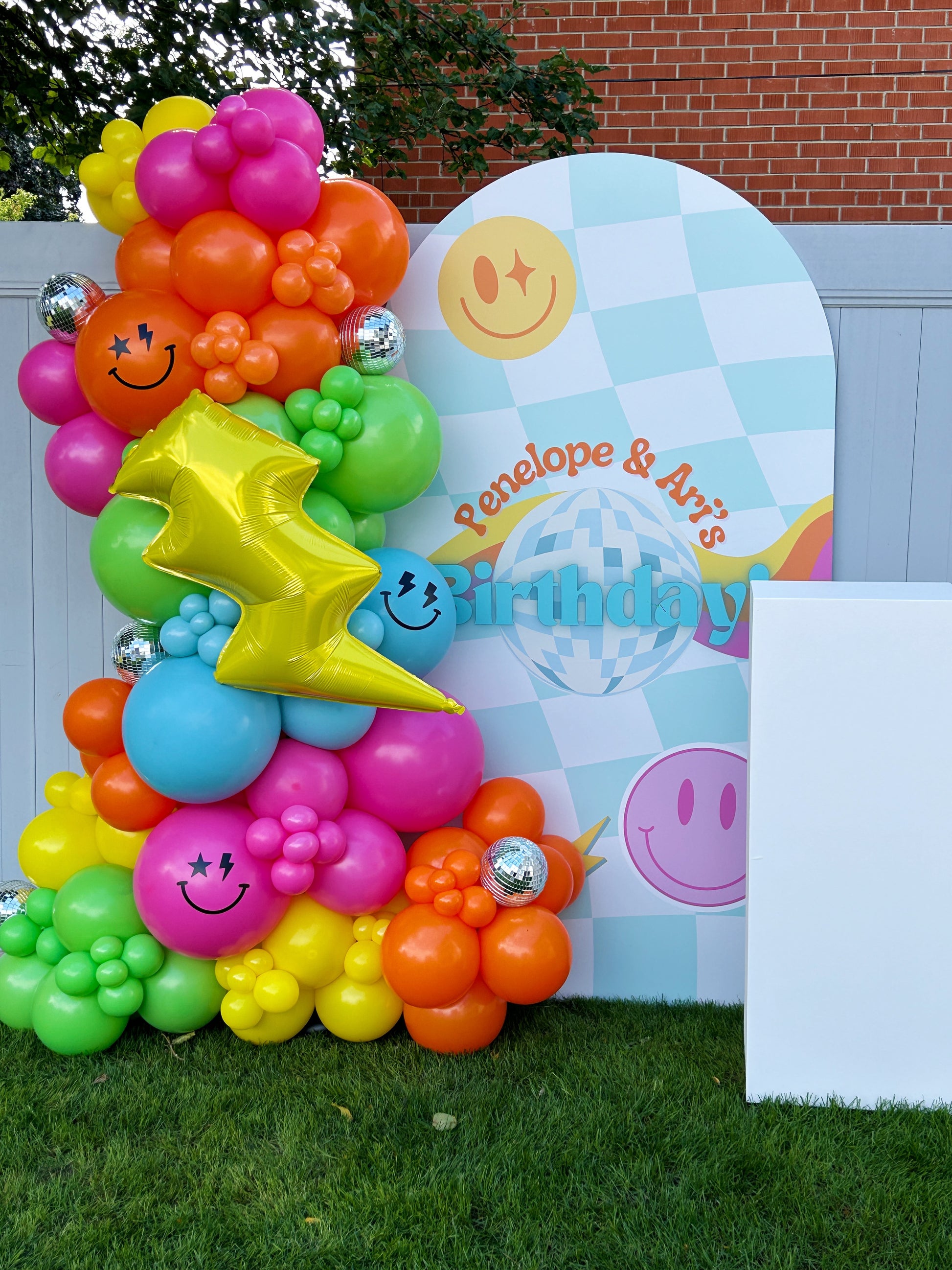 custom backdrop with colourful smiley face balloon garland 