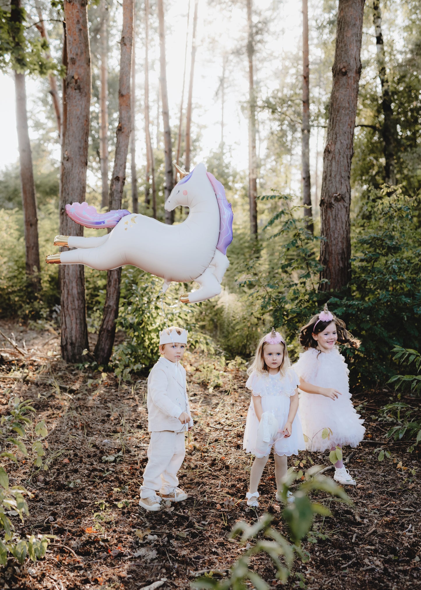 kids in a forest holding a unicorn foil balloon 