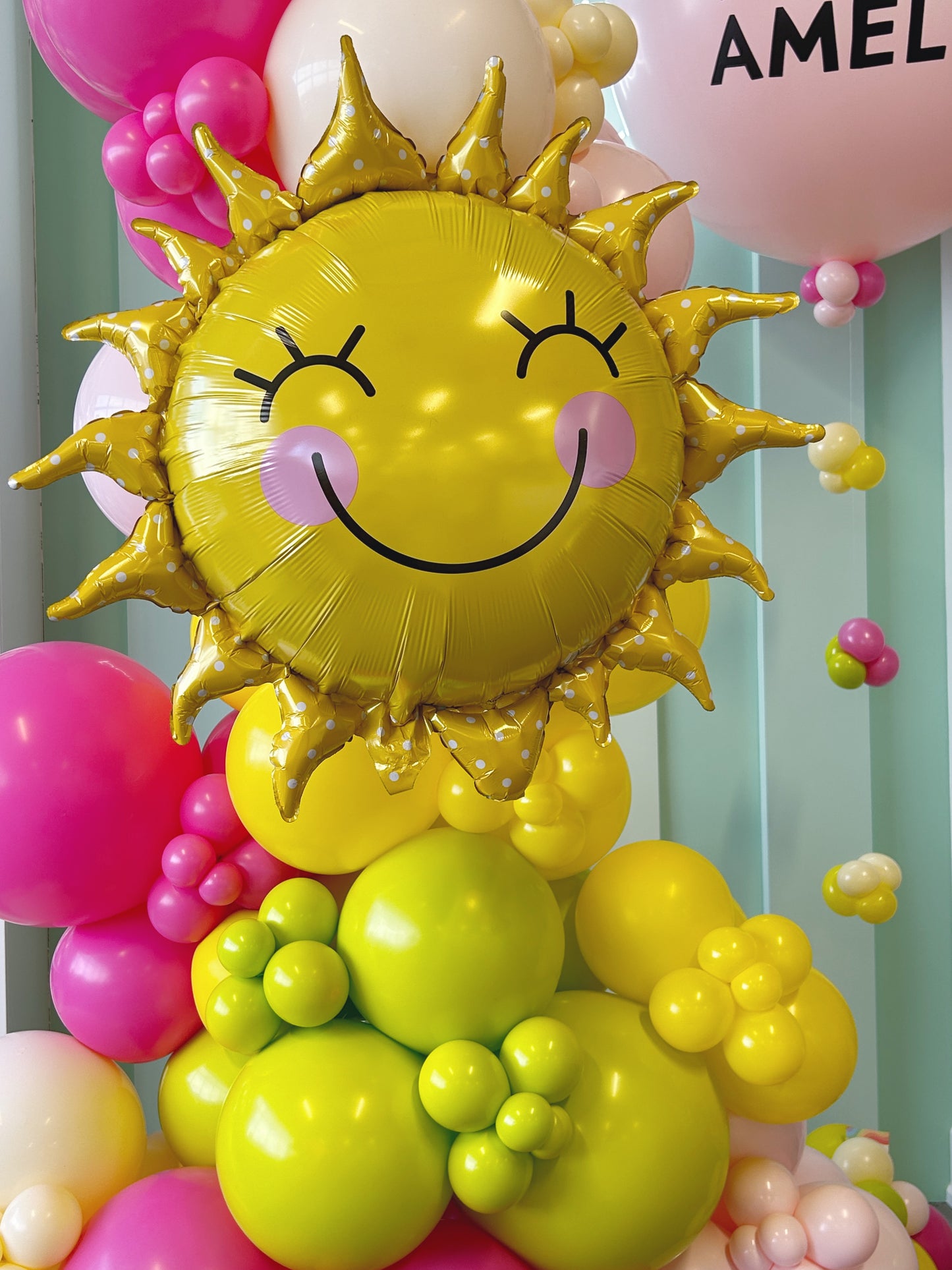 bright colourful balloon garland featuring a smiling sun foil balloon 