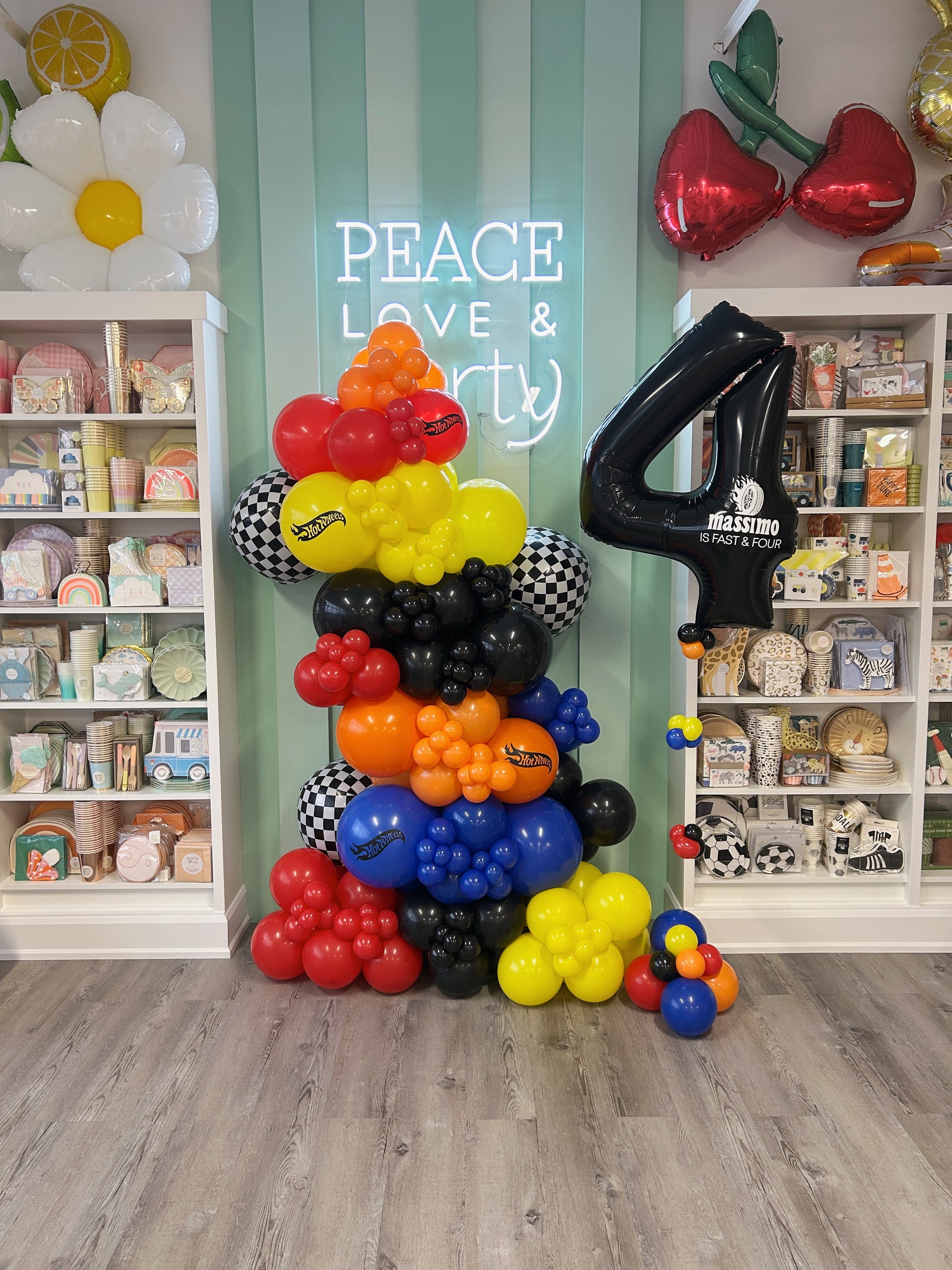 hot wheels themed balloon garland in orange, red, yellow, black, blue and checkered balloons - personalized with hot wheel logos + a foil number balloon