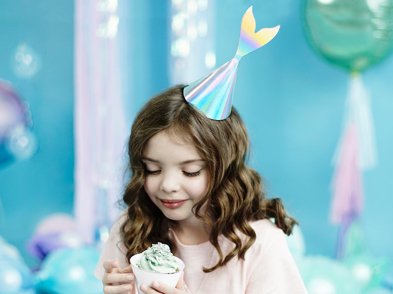 little girl eating cupcake wearing the mermaid tail party hat