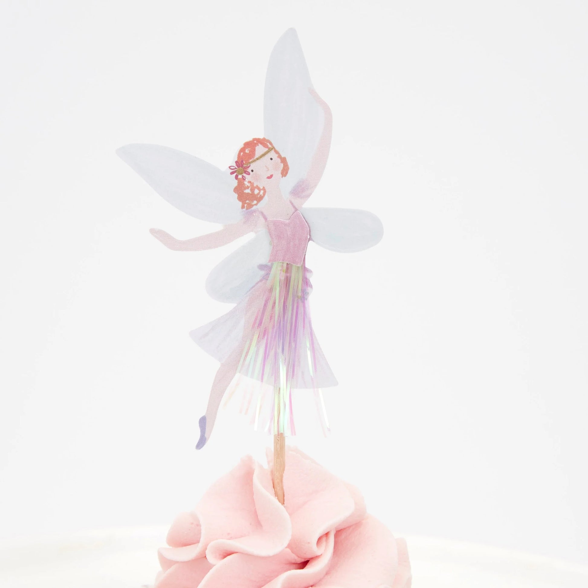 A cupcake with a fairy wearing a purple dress on top of it.