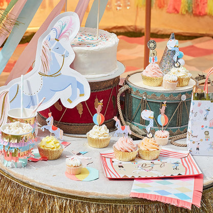 Circus-themed birthday party table with cake, cupcakes, and decorations