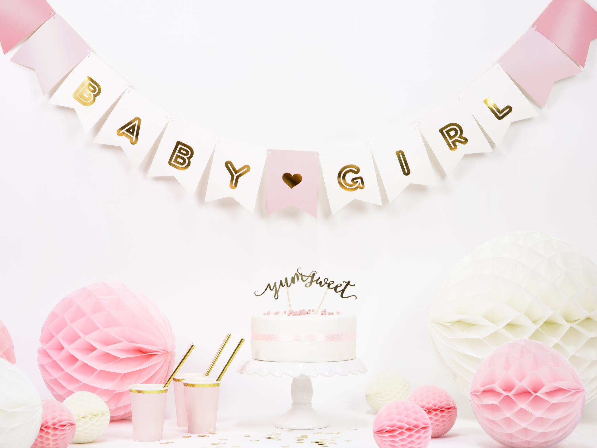 baby shower setup with baby girl banner and light pink honeycombs and decor 