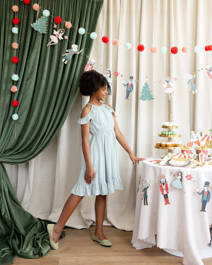 nutcracker hanging banner with girl posing beside a nutcracker inspired party table 