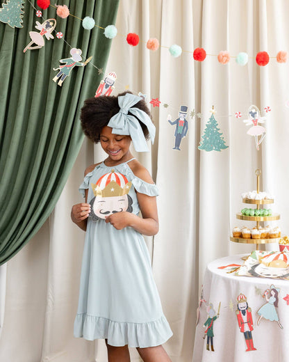 nutcracker hanging banner with girl holding a nutcracker shaped paper plate 