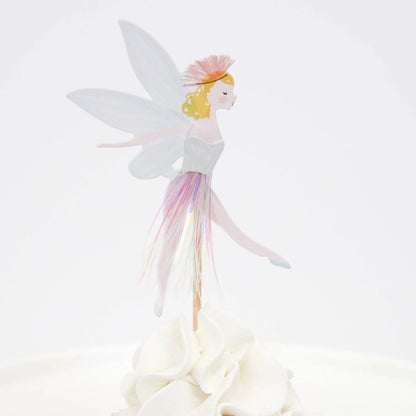 A cupcake with a fairy wearing a fringe skirt on top of it.