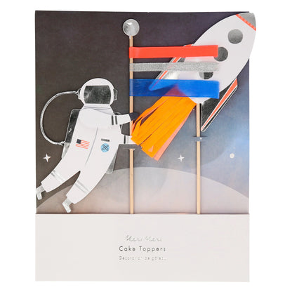 Packaged cake toppers featuring a spaceman with a flag and a rocket blasting off