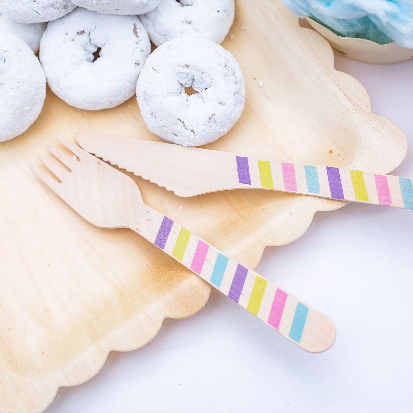 Striped wooden fork and knife on a plate with donuts