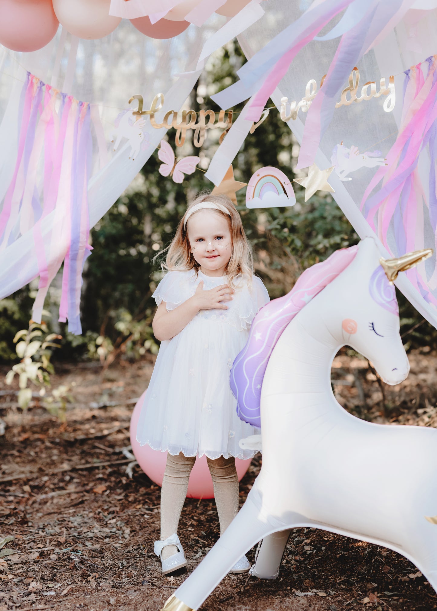 unicorn foil balloon with birthday girl posing beside it 