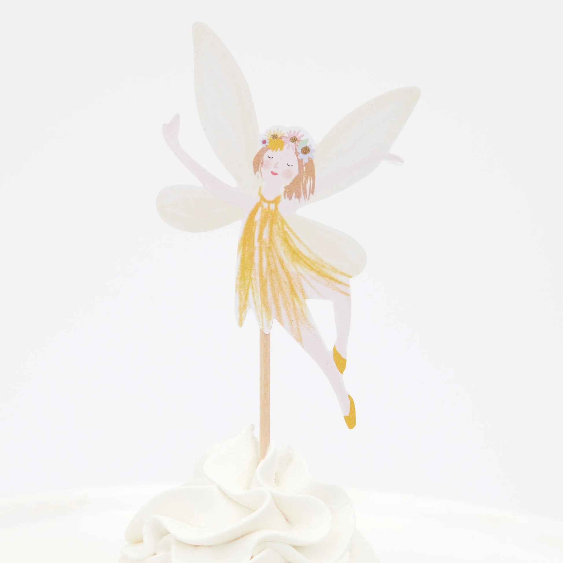 A cupcake with a fairy wearing a yellow dress on top of it.