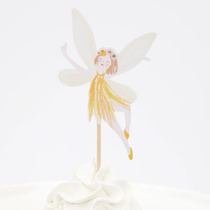 A cupcake with a fairy wearing a yellow dress on top of it.